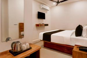 um quarto com uma cama, uma mesa e um espelho em OYO HOTEL R CK INN em Rajkot