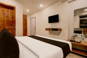 um quarto com uma cama e uma televisão na parede em OYO HOTEL R CK INN em Rajkot