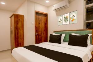 um quarto com uma cama grande e almofadas pretas e brancas em OYO HOTEL R CK INN em Rajkot