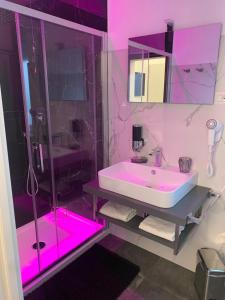 uma casa de banho com um lavatório e um chuveiro com iluminação rosa em JeVi Stars Rooms em Tropea