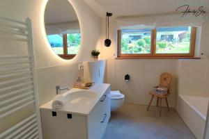 a bathroom with a sink and a toilet and a mirror at Homely Stay Velosoph Quartier - Familienfreundliches Ferienhaus mit 3 Schlafzimmern, 300m zur Ski-Piste, E-Auto Ladestation in Bayrischzell