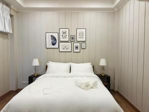 une chambre avec un grand lit blanc avec des serviettes dessus dans l'établissement Wiengket Heritage 1964, à Bangkok