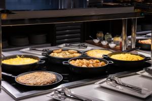 a buffet with many dishes of food in pans at Catalonia Atenas in Barcelona