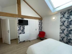 una camera con un letto bianco e una sedia rossa di Le Relais de 40 Sous a Aubergenville