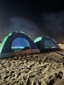 two tents on a sandy beach at night at Dubai Tourism and Travel Services in Hunaywah