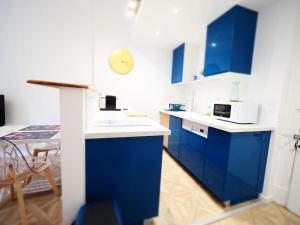 a blue and white kitchen with blue cabinets and a table at Les Ambassadeurs quartier Opéra in Vichy