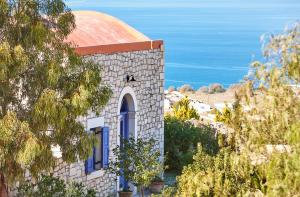 une église avec un toit rouge et une vue sur l'océan dans l'établissement Orelia Cretan Deluxe Apartments, à Kamilárion