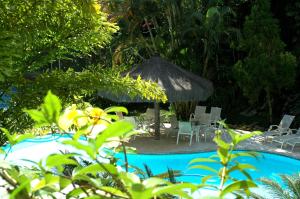 a pool with an umbrella and chairs and a table at Hotel Itapemar - Ilhabela in Ilhabela