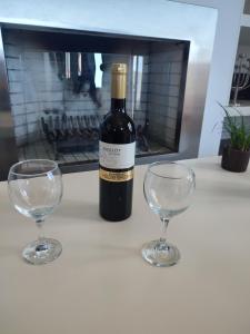 Krinos Suite-Magnificent Sea view في خيرسونيسوس: زجاجة من النبيذ وكأسين من النبيذ على منضدة