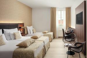 プラハにあるMichelangelo Grand Hotelのベッド2台とデスクが備わるホテルルームです。