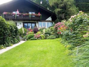 ein Haus mit einem Garten mit Blumen davor in der Unterkunft Blumenpension Strauss - Ferienwohnungen in Ossiach