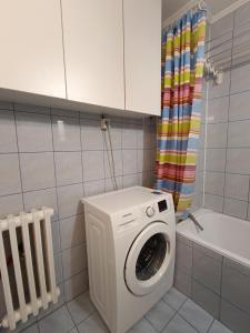 a washing machine in a bathroom with a shower curtain at Aura apartman Sarajevo in Sarajevo