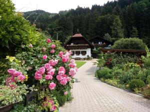 un jardín con rosas rosas frente a un edificio en Blumenpension Strauss - Ferienwohnungen, en Ossiach