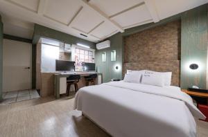 Schlafzimmer mit einem großen weißen Bett und einem Schreibtisch in der Unterkunft Hotel Trip in Incheon
