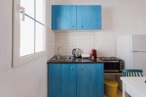 a kitchen with blue cabinets and a sink at Studios Eliza in Livadi