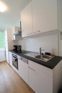 una cocina con armarios blancos y fregadero en Exclusive serviced flat on Taborstraße, en Viena