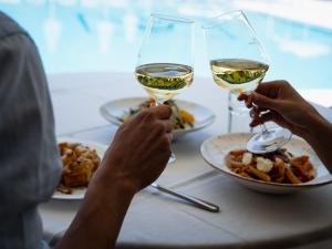 Dracos Hotel في بارغا: شخصان يشربان النبيذ الأبيض على طاولة مع الطعام