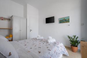 a white bedroom with a large bed and a tv at Studios Eliza in Livadi