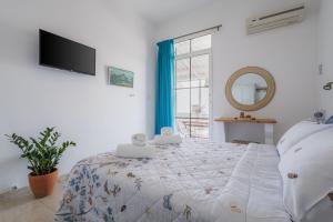 a bedroom with a bed and a tv on the wall at Studios Eliza in Livadi