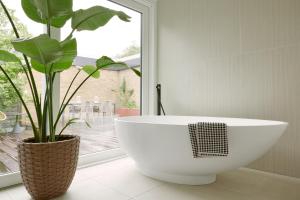 een badkamer met een groot wit bad en een plant bij Homefy Luxury Bungalow - 5 Pax - 2 Bath - Garage in Ratingen
