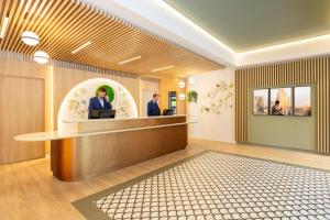 a lobby with two men at a reception desk at Citadines Toison d’Or Brussels Aparthotel in Brussels