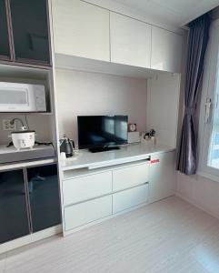 a kitchen with white cabinets and a flat screen tv at Sea View Doubleroom in Incheon