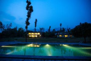 a swimming pool at night with a house in the background at Hideaway By Aahma in Rāmnagar