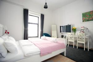 a white bedroom with a white bed and a desk at BIT apartments in Ljubljana