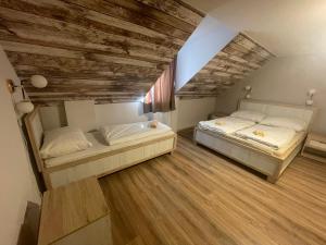 two beds in a room with wooden floors at Mátyus Udvarház Kengyel Fogadó Eger in Eger