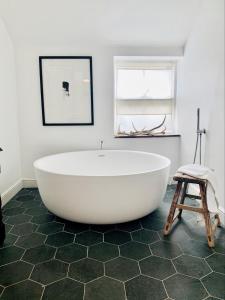 een groot wit bad in een badkamer met een kruk bij The Croft Place of Architectual Interest in Lochearnhead