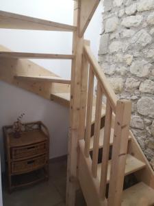 eine Holztreppe in einem Zimmer mit einer Steinmauer in der Unterkunft Agréable chambre privée avec entrée indépendante in Langeais