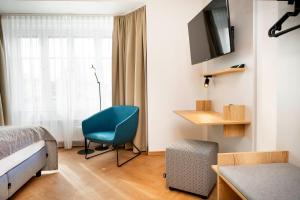 a bedroom with a bed and a blue chair and a window at Zum Lenz in Langau