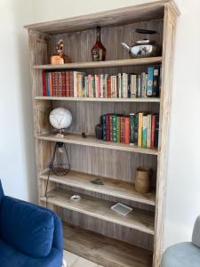 een boekenplank gevuld met boeken in een woonkamer bij Clos Phitarra, charmant gîte pour 2 personnes à 7 mns d'Etretat in Les Loges