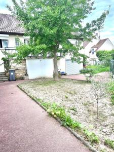 un arbre dans une cour à côté d'une maison dans l'établissement La Perle, proche Roissy CDG, Paris, Parc asterix, Disney, à Moussy-le-Vieux
