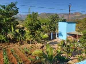 a garden with a blue building and mountains in the background at Varshav Villa in Pune