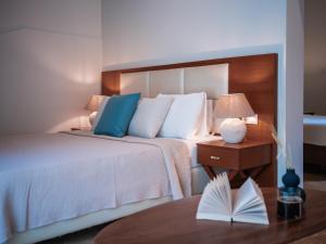 Dracos Hotel في بارغا: غرفة فندقية بسرير وطاولة مع كتاب