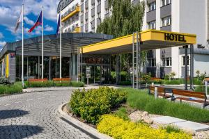 布拉格Wellness Hotel Step - Czech Leading Hotels的一家酒店，楼前有长椅和旗帜