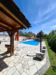 eine Steinterrasse mit Swimmingpool und Sonnenschirm in der Unterkunft Frühstückspension Wahl in Ruprechtshofen