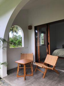 una camera con un tavolo, due sedie e un letto di Rumah Markisa Batukaras a Batukaras
