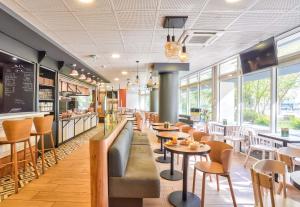 a restaurant with tables and chairs and windows at B&B HOTEL Paris Malakoff Parc des Expositions in Malakoff