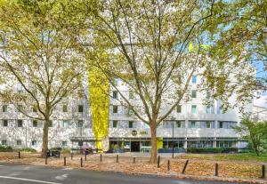 un edificio blanco con árboles delante de él en B&B HOTEL Paris Malakoff Parc des Expositions, en Malakoff