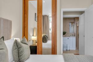 - une chambre avec un lit et un grand miroir dans l'établissement One Bed Serviced Apt near Holborn in Chancery Lane, à Londres