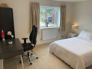 1 dormitorio con cama, escritorio y silla en Home, en Portishead