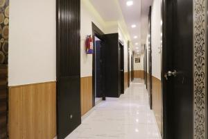 a hallway with black doors and a white tile floor at Flagship Hotel Sangeet in Faridabad