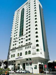 un edificio blanco alto con coches estacionados frente a él en Howard Johnson by Wyndham Abu Dhabi Downtown en Abu Dabi