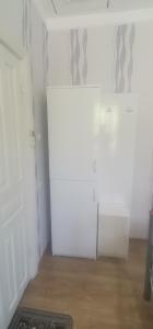een witte koelkast in een kamer met een houten vloer bij Guest House Darejani in Koetaisi