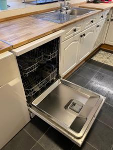 an open dishwasher with its door open in a kitchen at Lovely house next to Euchan River in Sanquhar
