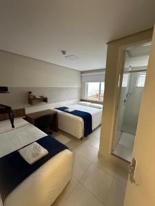 a hotel room with two beds and a shower at Hotel Imperatriz in Telêmaco Borba