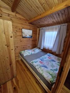 a bed in a wooden cabin with a window at OKW Bursztyn Międzywodzie in Międzywodzie