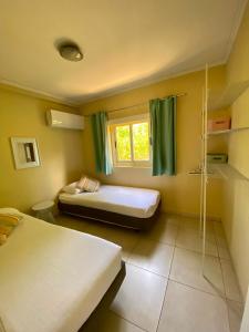 a small bedroom with two beds and a window at Montana Eco Resort Aruba in Oranjestad
